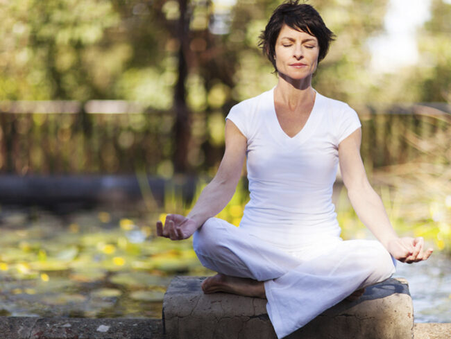 faça_da_sua_menopausa_uma_experiencia_positiva mulher sentada no parque meditando